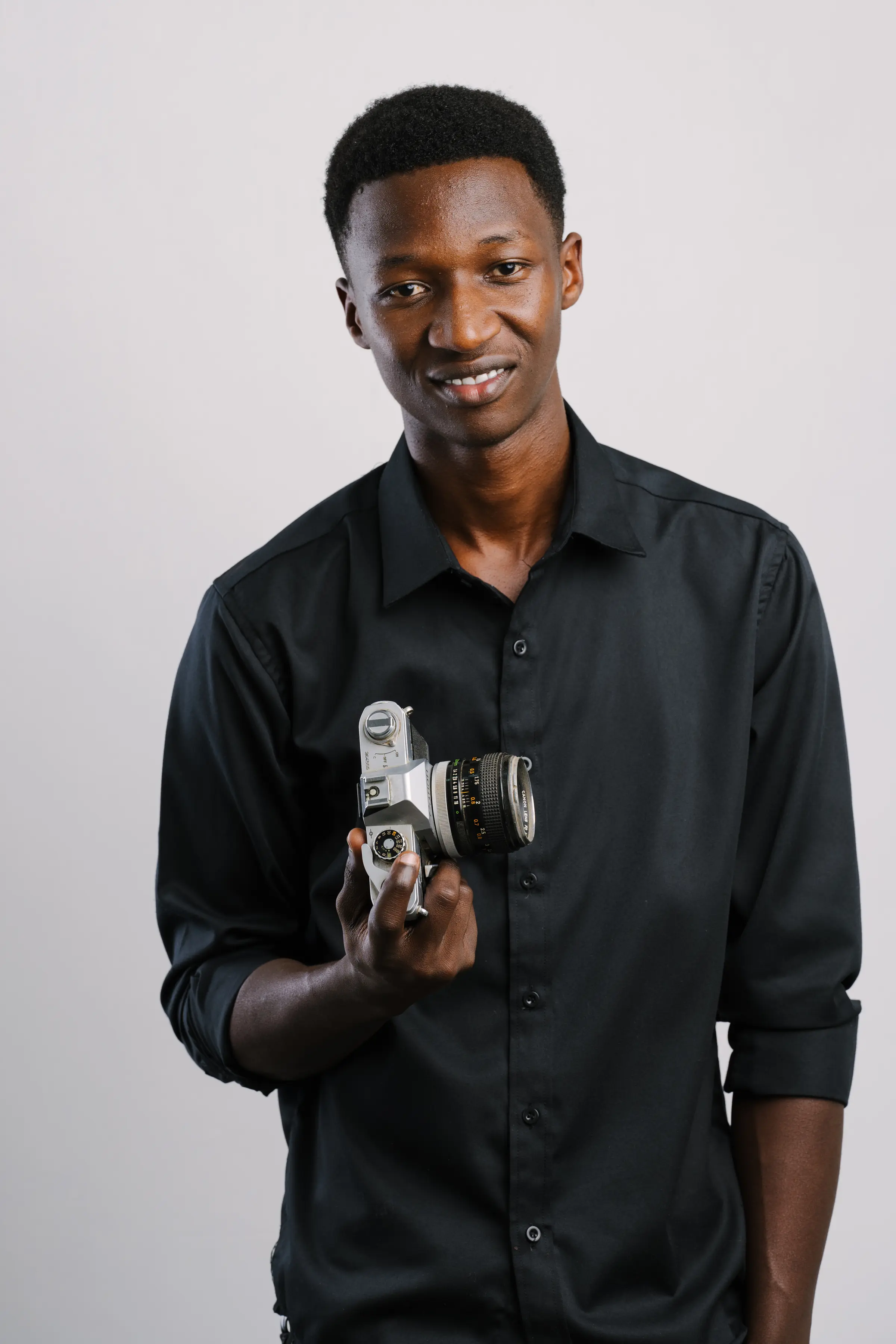 George Mollel in the studio, a vintage film camera in hand